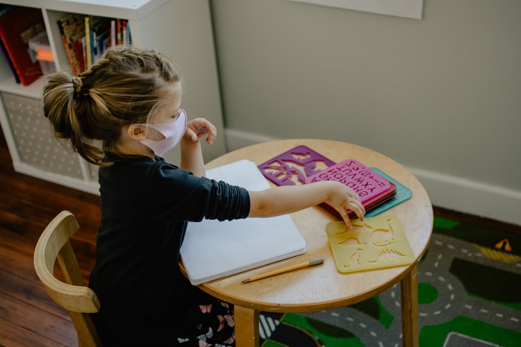 child with mask sitting in the classroom